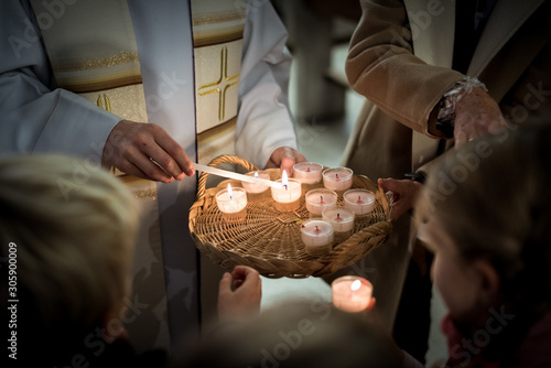 People gathering around Priest lighting candles photo
