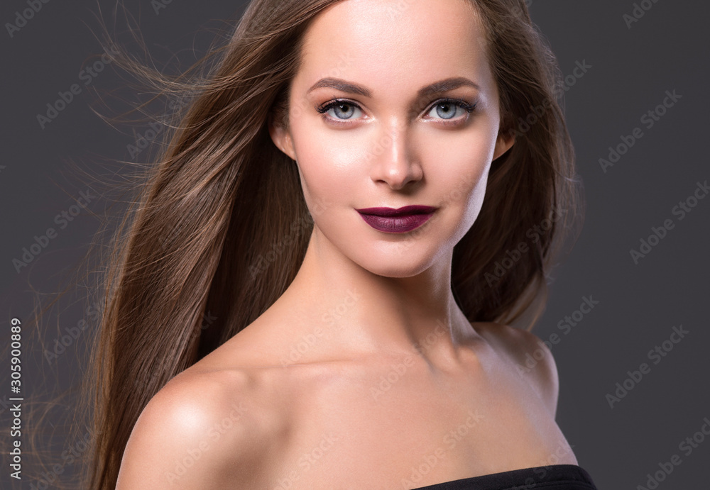 Naklejka premium Beautiful hairstyle woman face long smooth brunette hair red lips over gray background