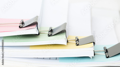 Stack of office working document with black paper clip folder separated group by pastel note paper