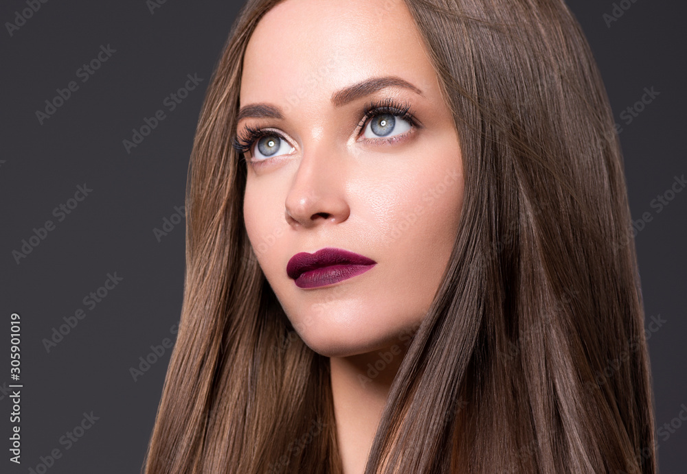 Fototapeta premium Beautiful woman eyes face long smooth brunette hair red lips over gray background