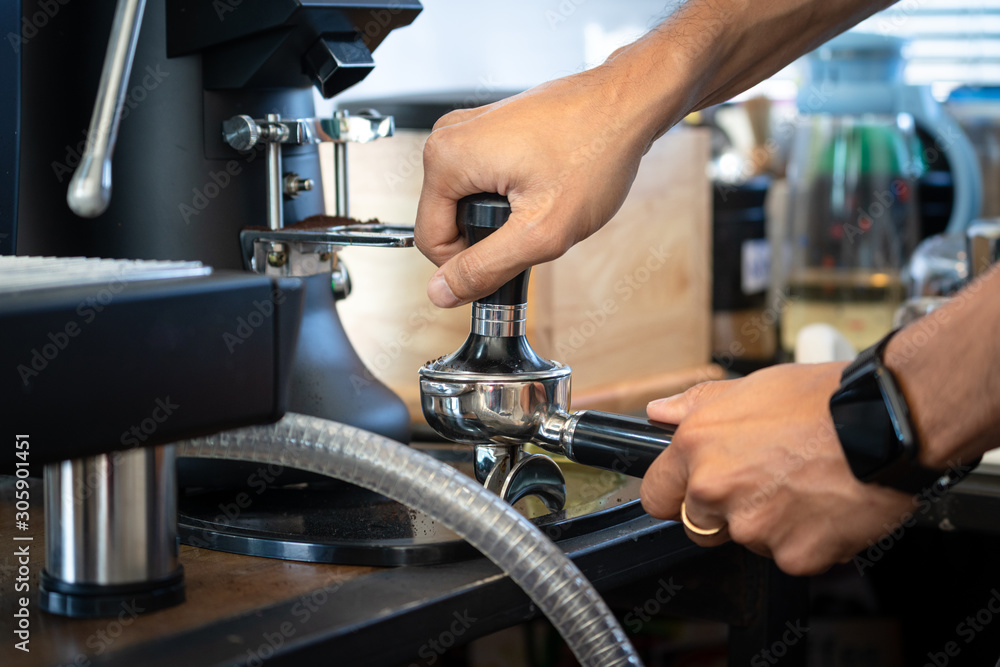 Coffee barista is pressing coffee beam into the filter block by using a temper. Close up and selective focus. Fresh coffee making photo action. Coffee barista is pressing coffee beam into the filter block by using a temper. Close up and selective focus. Fresh coffee making photo action.