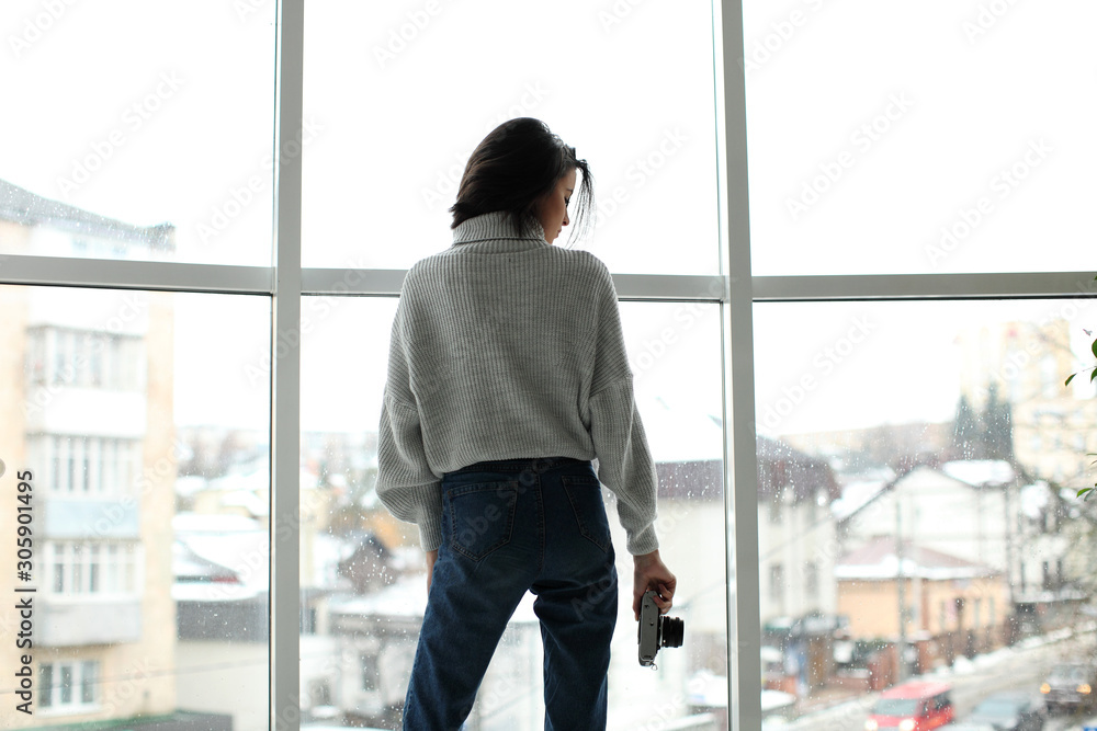 portrait of a beautiful girl with a camera standing by the window portrait of a beautiful girl with a camera standing by the window