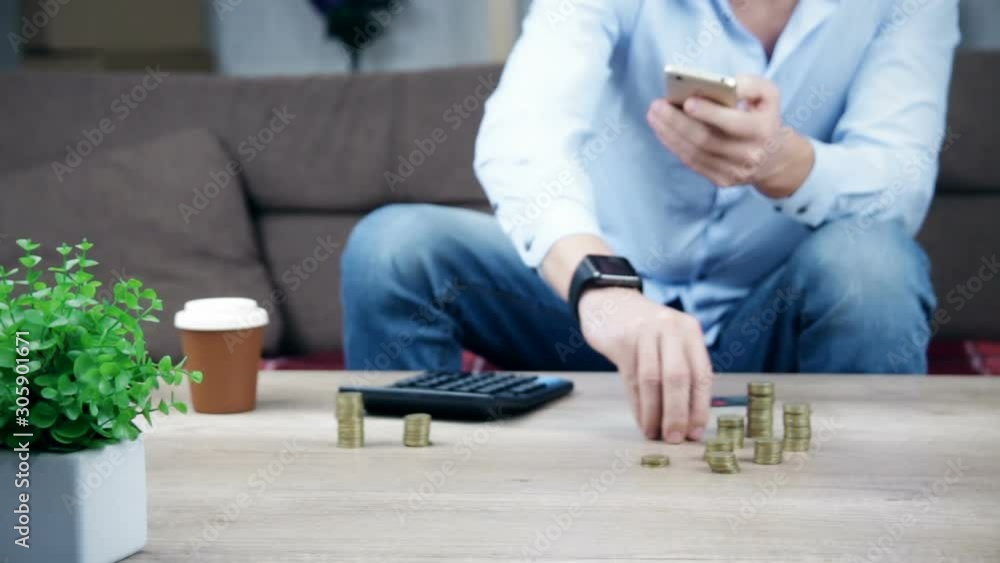 Young man sitting on the couch, using smart phone for online shopping with credit card on living backround. Indoor. Young man sitting on the couch, using smart phone for online shopping with credit card on living backround. Indoor.