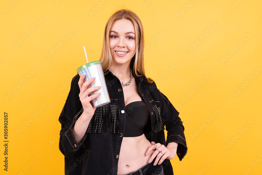 Young beautiful girl drinks cocktail on yellow background Young beautiful girl drinks cocktail on yellow background