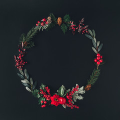 Christmas round frame made of natural winter things on dark blackboard. Flat lay background . Christmas wreath concept.