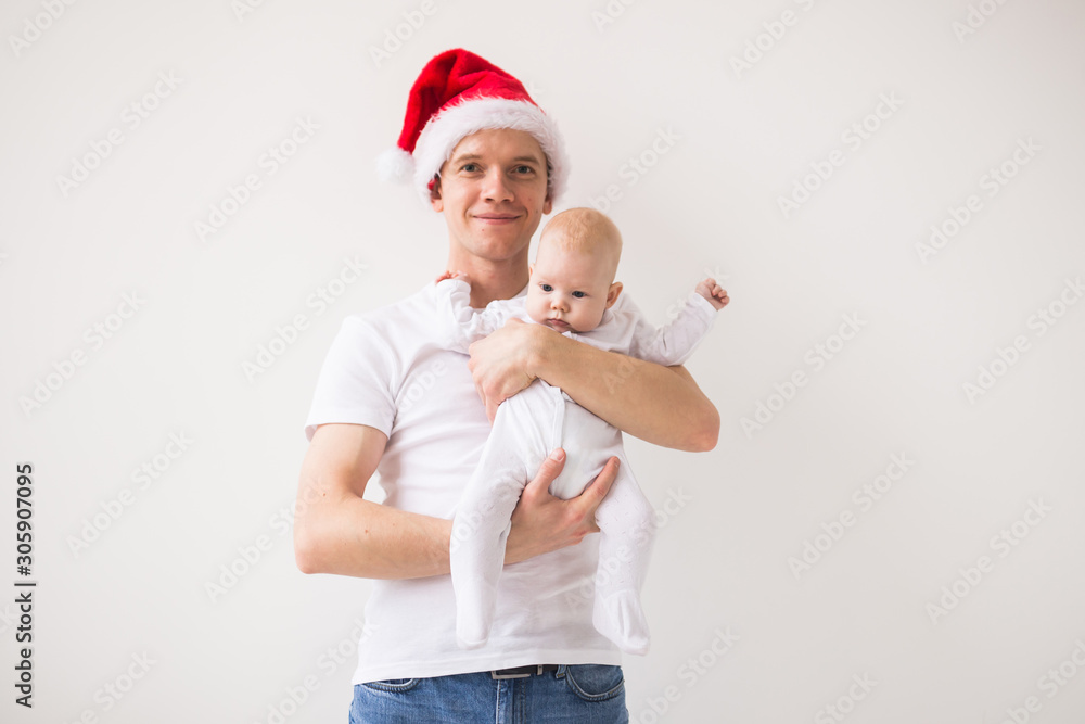 My first Christmas. Dad in santa hat holding his baby girl daughter on white background with copy space My first Christmas. Dad in santa hat holding his baby girl daughter on white background with copy space