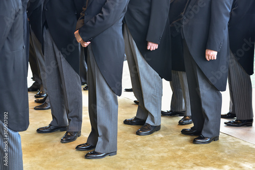 Men wearing the same tail coats at an official ceremony photo