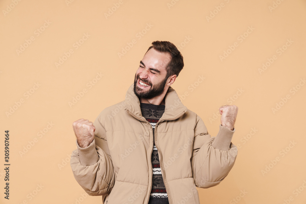 Image of positive man in winter jacket smiling and rejoicing as winner Image of positive man in winter jacket smiling and rejoicing as winner