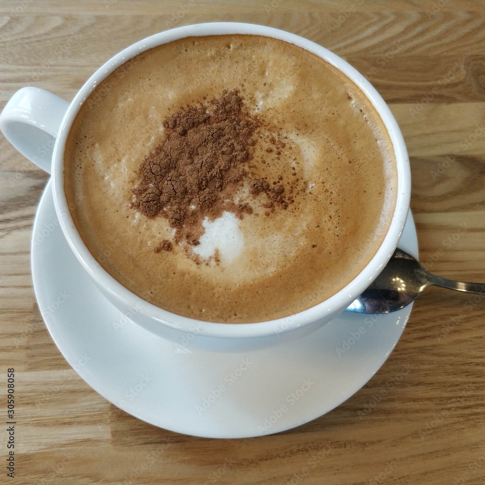White cup with coffee and cinnamon on a wooden table. White cup with coffee and cinnamon on a wooden table.