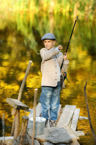 Kid fishing in a river, sitting on a wood pontoon © azhurfoto