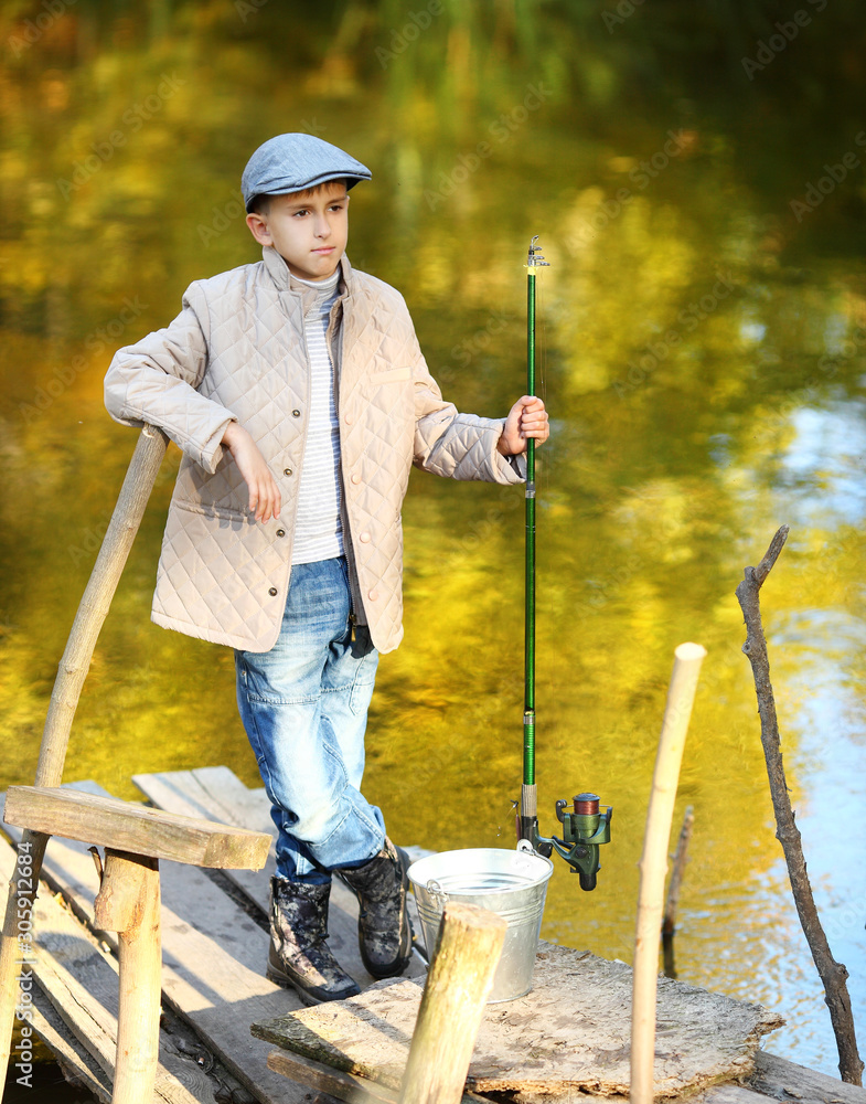 Kid fishing in a river, sitting on a wood pontoon Kid fishing in a river, sitting on a wood pontoon