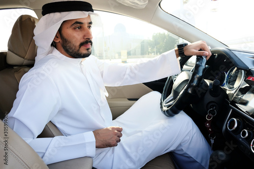 Driving Arab man holding steering wheels wearing kandura dish dash photo