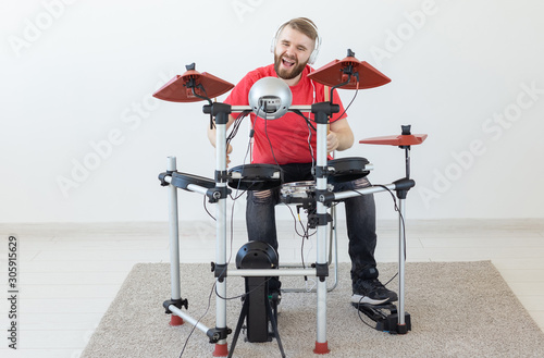 People, music and hobby concept - Man with white headphones playing the drums set over light background