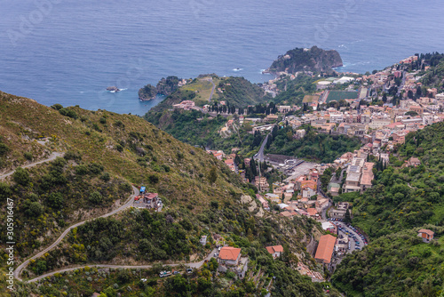 Hairpin road on a green mountain seen from Castelmola, small town on Sicily Island, Italy - Taormina city on background