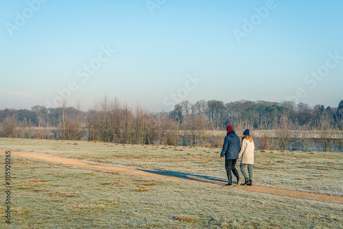 Man and woman walk hand in hand in a winter landscape