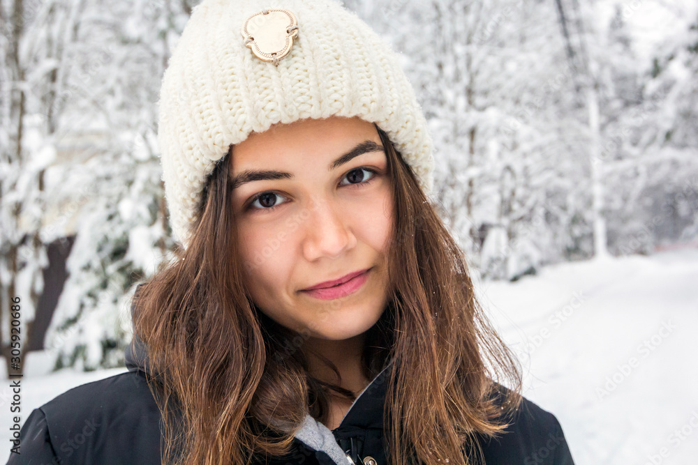 Portrait of woman in white knitted hat on background of snowy forest in winter frosty day, close-up Portrait of woman in white knitted hat on background of snowy forest in winter frosty day, close-up