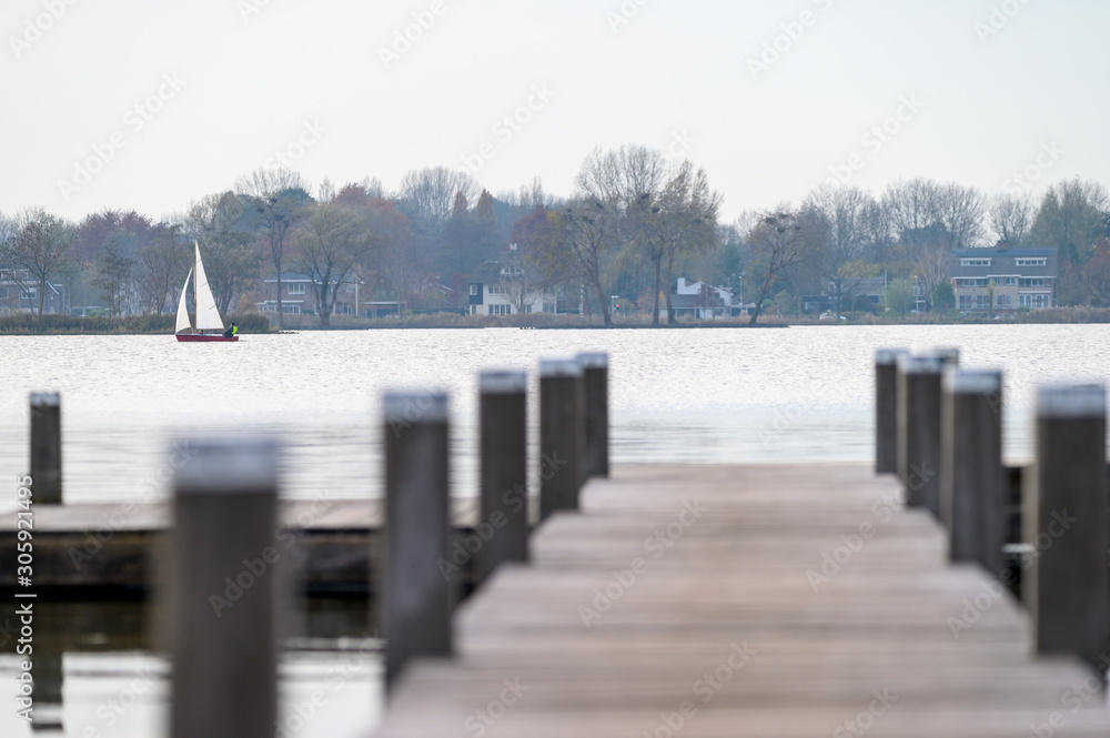 Scaffolding in a lake. A sailboat sails past.
