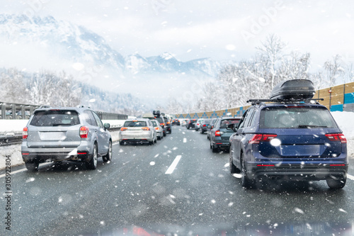 Winter highway with many different cars stucked in traffic jam due ti bad weather conditions. Vehicles on road during heavy snowstorm and blizzard on cold winter day in Austria near Germany border © Kirill Gorlov