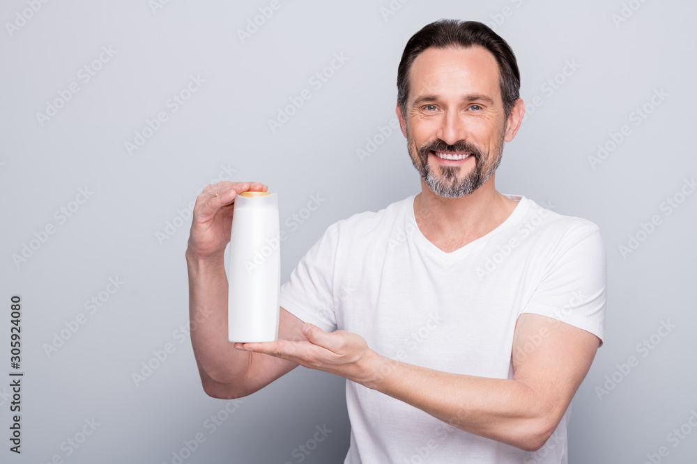 Photo of handsome aged man guy holding shampoo conditioner bottle two in one amazing effect advertising buyers wear white t-shirt isolated grey color background Photo of handsome aged man guy holding shampoo conditioner bottle two in one amazing effect advertising buyers wear white t-shirt isolated grey color background