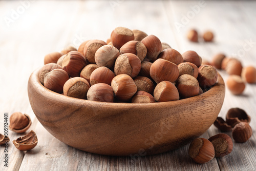Hazelnuts in bowl on white wooden background. Selective focus.