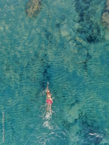 Vista aerea hombre nadando en el mar de la isla de Mallorca sobre aguas cristalinas v concepto de vacaciones, verano, viajar, turismo y disfrutar
