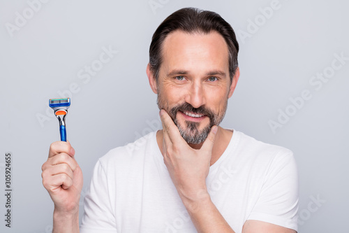 Closeup photo of handsome mature handsome man looking mirror use razor going to shave beard metrosexual neat guy wear white t-shirt isolated grey color background