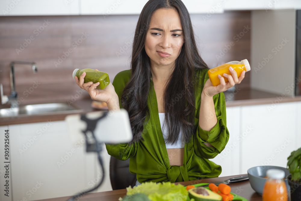 Fototapeta premium Annoyed housewife holding two bottles of sauces