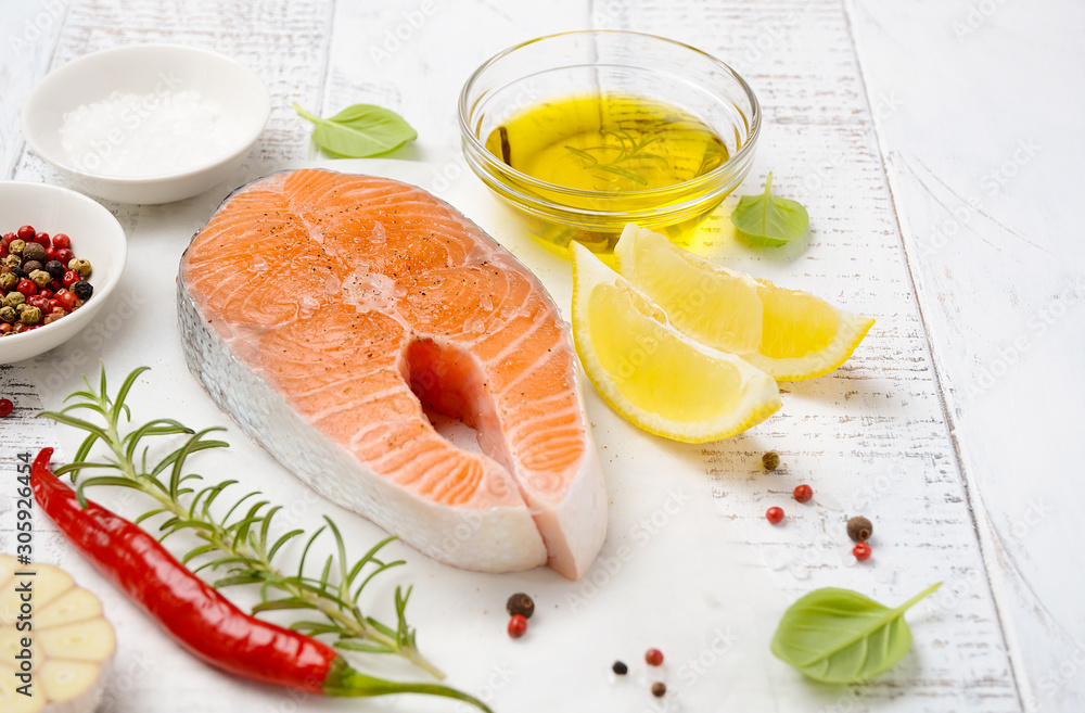 Fresh raw salmon steak with lemon, olive oil and spices on white wooden background. Ingredient for making healthy dinner. Healthy diet concept. Fresh raw salmon steak with lemon, olive oil and spices on white wooden background. Ingredient for making healthy dinner. Healthy diet concept.