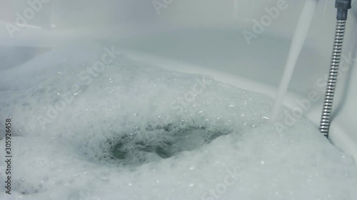Water running in to the bathtub, fulled bathtub. Preparing bath for relax.