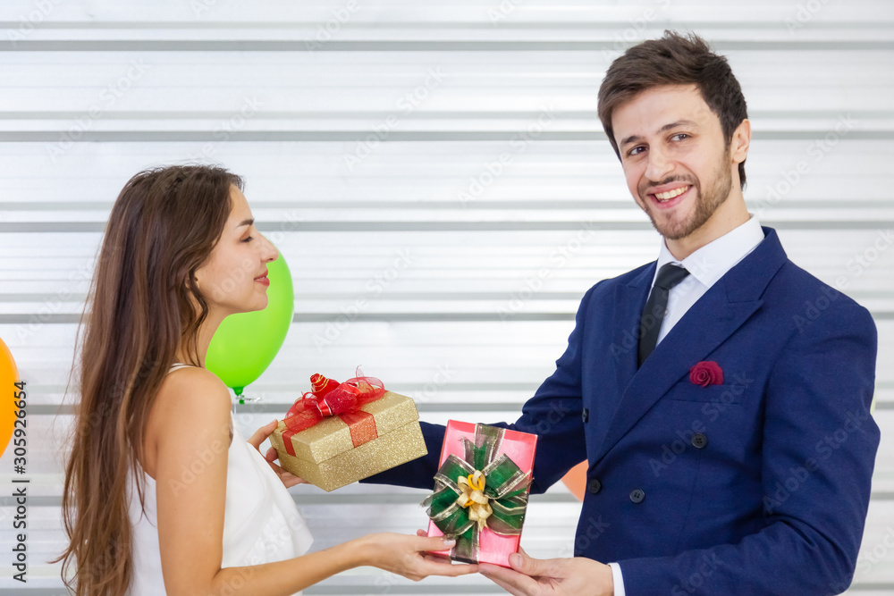 Romantic lovers smiling and exchanging gifts in the midst of a festive celebration that decorated with balloons. Concept of New Year, Christmas, Woman's Day, Valentine Party. Romantic lovers smiling and exchanging gifts in the midst of a festive celebration that decorated with balloons. Concept of New Year, Christmas, Woman's Day, Valentine Party.