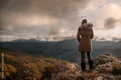 Woman in coat looking at mountain view in Corsica