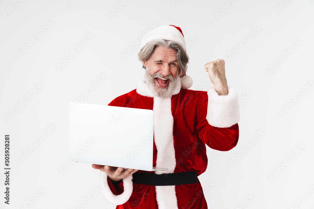 Portrait of delighted gray man making winner gesture and using laptop Portrait of delighted gray man making winner gesture and using laptop
