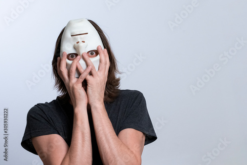 Strange psychedelic concept. A man with long hair holds an inverted mask on his face. The male body characterizing the problems of the psychophysical state of a person or mental disorder. photo