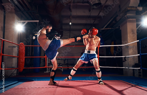 Two athlete kickboxers practicing kickboxing in the ring at the health club