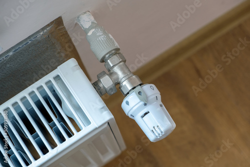 Closeup of heating radiator valve for comfortable temperature regulation on metal radiator on inrerior wall.