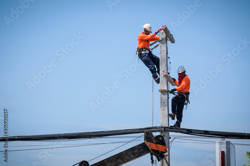 Electricians are climbing on electric poles to install and repair power lines.