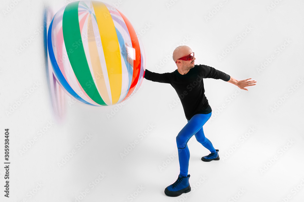 Athlete bald man in sportswear playing with beach ball in studio over white background.