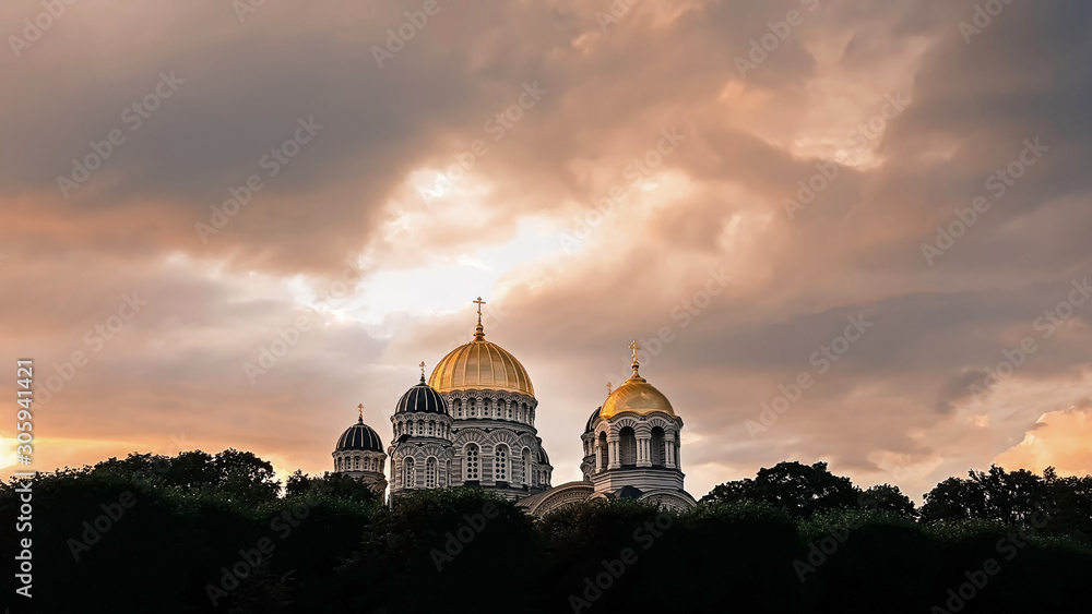 Beautiful view of golden towers of Orthodox cathedral isolated on dramatic  sunset sky. Atmospheric mood. Religion concept.