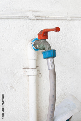 water tap with rubber band on white wall