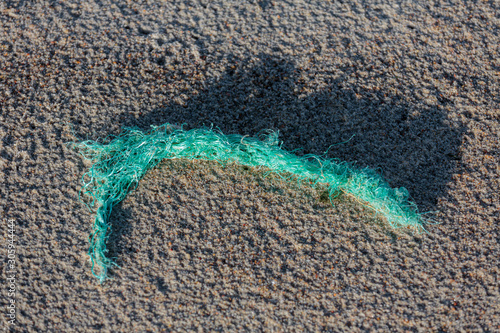 Environmental pollution - a part of an old worn plastic rope, brought back by the sea as garbage photo