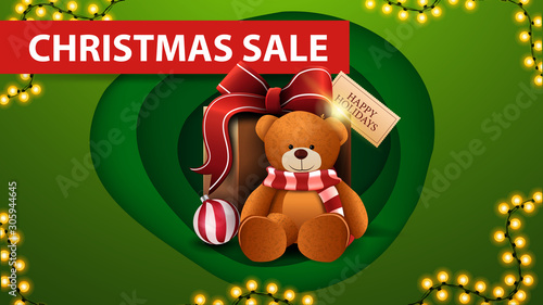Christmas sale, green discount banner in paper cut style, garland and present with Teddy bear
