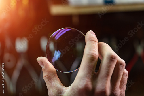 ophthalmologist hands close up, showing a glass lens for spectacles. Blurred background. Ophtalmologist equipment. Vision correction concept. photo