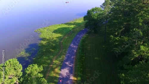 Aerial footage by drone over Lake Wilhelmina with fishing boat and the walking path that follows the shore., Mena, Arkansas.