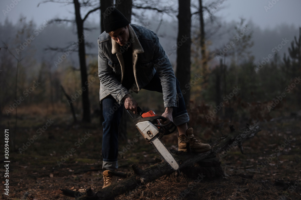Lumberman work with a chainsaw in the forest. Strong lumberjack with the chainsow in the forest.Stylish lumberman getting ready for work. Lifestyle. Hard work in the forest. Illegal logging. Lumberman work with a chainsaw in the forest. Strong lumberjack with the chainsow in the forest.Stylish lumberman getting ready for work. Lifestyle. Hard work in the forest. Illegal logging.