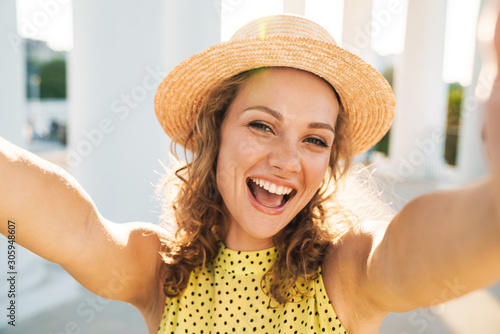 Pleased woman walking outdoors by street take a selfie