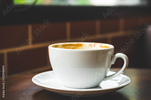 close up modern hot black coffee the cappuccino on wood background with coffee bubble foam pattern and texture in white cup looking and feel so delicious on glasses table in coffee shop.