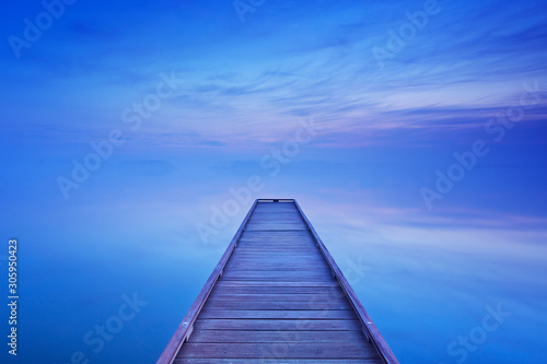 Jetty on a still lake at dawn in The Netherlands
