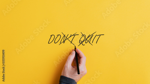 Male hand crossing off a Don't quit sign to change it into a Do it message photo