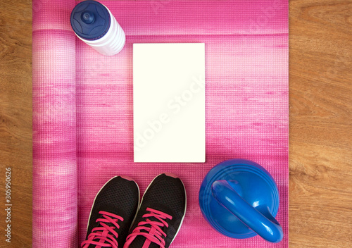 Healthy lifestyle items - sneakers, water bottle, kettlebell, yoga mat with a blank motivational message poster on a bright pink background