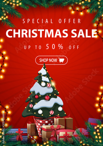 Special offer, Christmas sale, up to 50% off, red vertical discount banner with Christmas tree in a pot with gifts, frame of Christmas tree branches, garlands and presents